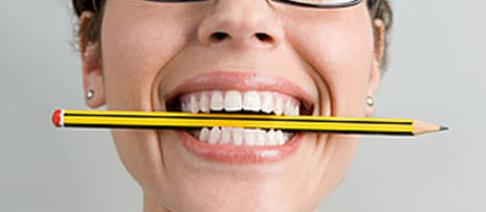 Una mujer tiene un lápiz en la boca, lo que le obliga a sonreír., generando emociones positivas como la felicidad.